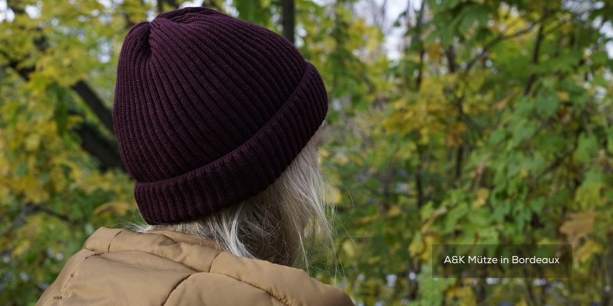 Mütze in der Farbe Bordeaux. Eine junge Frau ist im Wald und trägt die Mütze in der Natur.